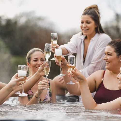 Five girls in a hot tub holding up wine glasses to cheers each other at Spring Creek Vacations
