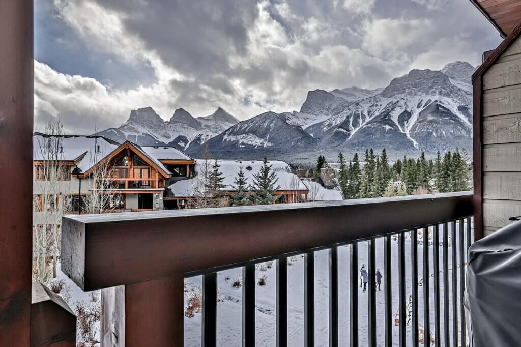view from a balcony of a Spring Creek Vacations suite overlooking the mountains in Canmore with a cloudy, stormy sky 