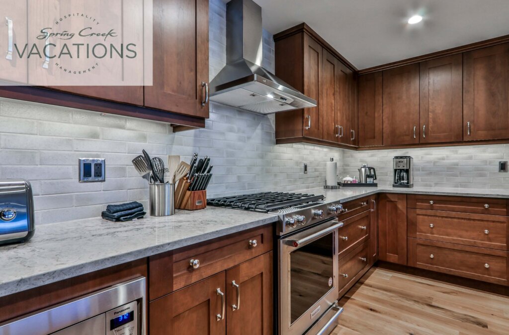 A gourmet, modern kitchen with dark wooden cabinetry, white tile backsplash and hardwood floors in a White Spruce Lodge luxury vacation rental suite at Spring Creek Vacations in Canmore, Alberta.