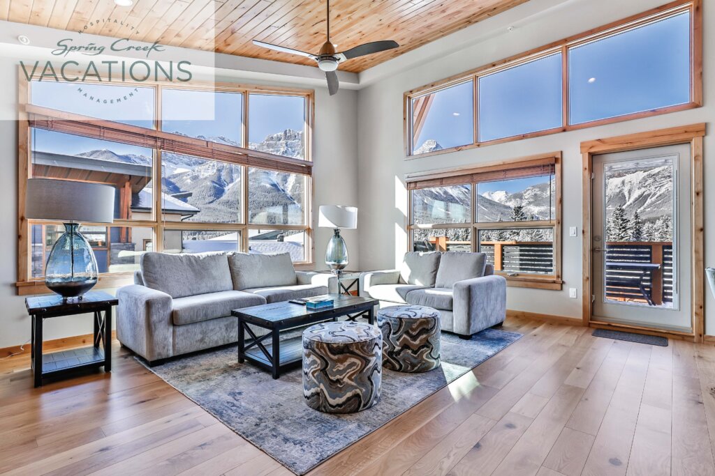 A bright, modern living room with floor to ceiling windows and hardwood floors in a White Spruce Lodge luxury rental suite at Spring Creek Vacations in Canmore, Alberta