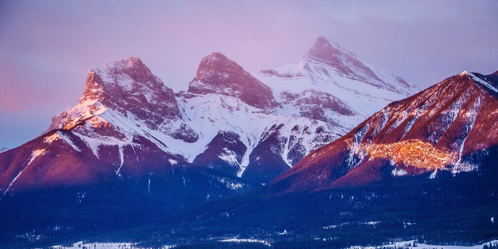 A sunrise over the snowcapped Three Sisters mountains in Canmore, Alberta.