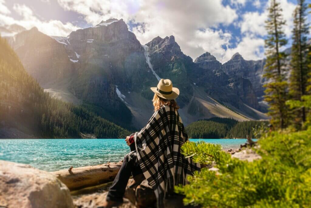 Women facing a blue lake looking at the Rocky Mountains. 