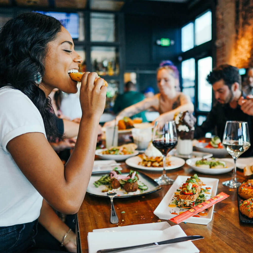 A woman takes a bite to eat from her food while dining with friends,