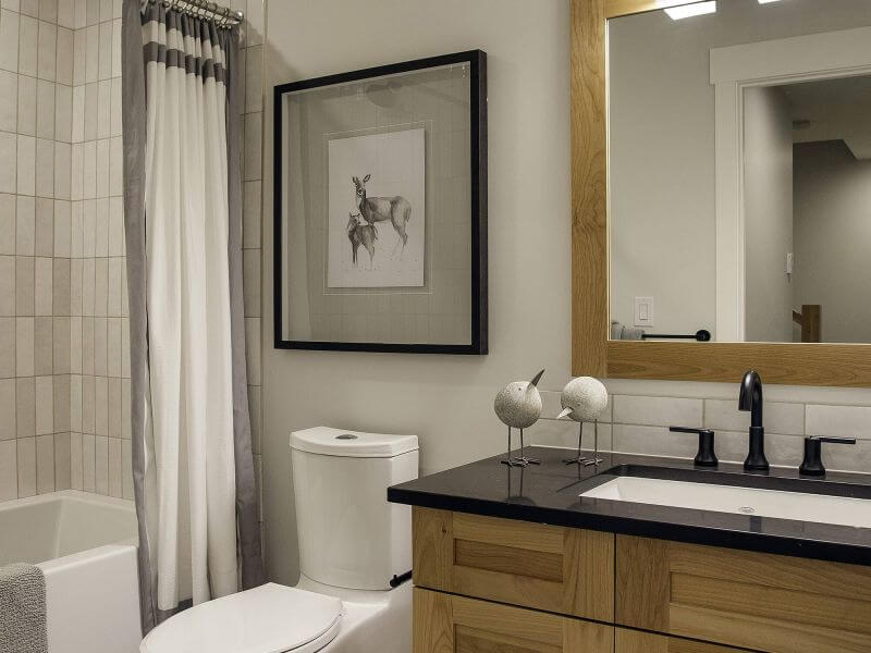 A luxury bathroom with white and grey tiles and wooden finishes in a Tamarack Lodge luxury condo.