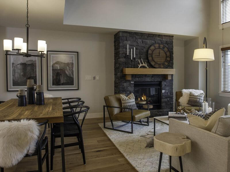 An open concept dining and living room with neutral tones, wooden accents and flooring and bright light in a luxury Tamarack Lodge condo.