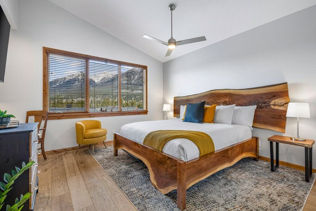 One of the Tamarack Lodge Unit 403A's bedrooms, with hardwoord floors, bright natural light, and a comfortable large bed with modern luxury finishes, located at Spring Creek Vacations in Canmore, Alberta.