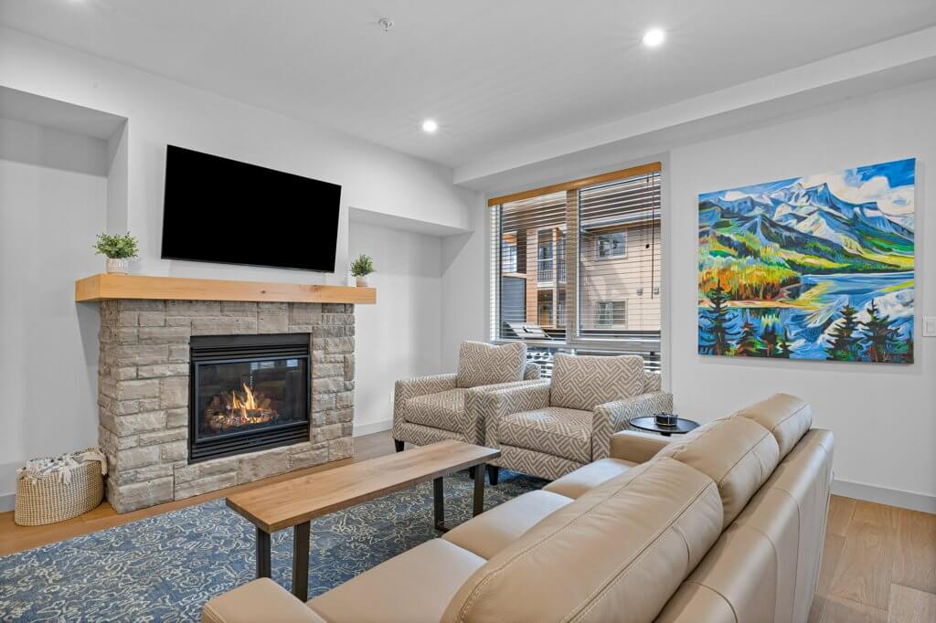 living room with a couch, 2 arm chairs, and a tv over a fire place