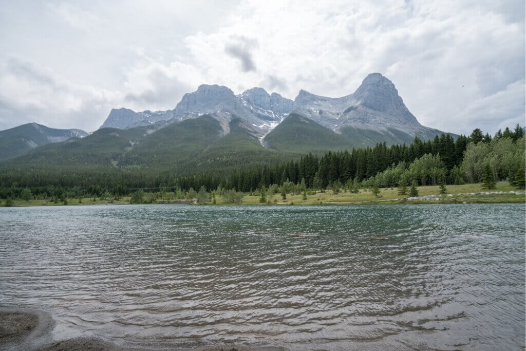 Quarry Lake on a misty, grey day, with the mountains and forests stretching in the background, one of the best photo spots in Canmore, Alberta.