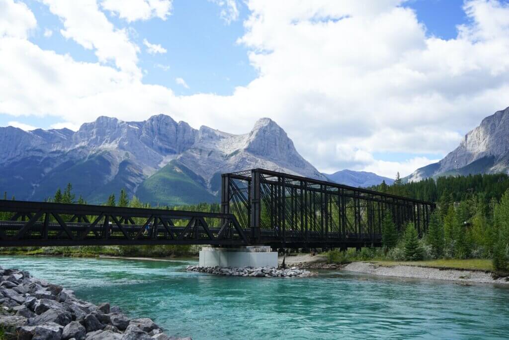 The Canmore Engine Bridge, one of the best photo spots in Canmore, stretches over the vibrant blue waters of the Bow River with the Canadian Rockies in the background.