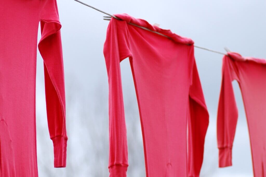 A row of red long johns hang off of a clothing line.